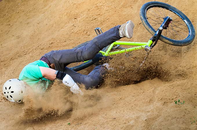 A guy crashing into dirt on his bike