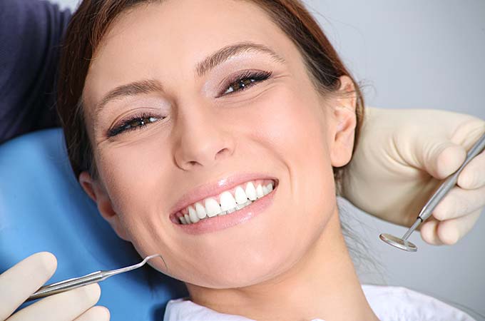 woman smiling with dental instruments around her face