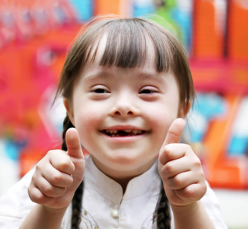 a little girl with down syndrome giving thumbs up